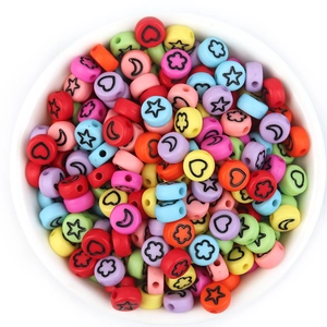 Flat round acrylic beads in assorted colors with star and heart patterns in a white bowl