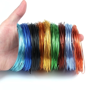 Hand holding assorted colorful aluminum wire coils for DIY jewelry and model making