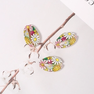 Macro detail of cowrie shell beads with painted daisy patterns and colorful floral designs