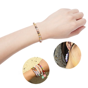 Detail van metalen gouden kralen, smile-letterarmbanden en veiligheidsspeld oorbellen