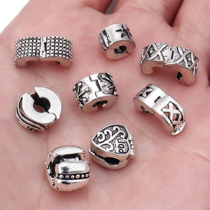 Antique silver stopper beads with heart and star patterns shown on a palm for scale