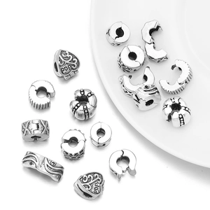 Antique silver plated spacer beads and clip charms for DIY jewelry making on white dish