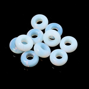 Macro shot of 11 opal glass wheel beads with blue fire on a black mirror background