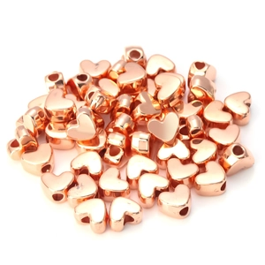 Detail van hartvormige kralen in roségoud met een centraal gat voor DIY-sieraden maken