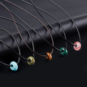 Minimalist natural stone bead necklaces on black ropes including malachite and tiger eye