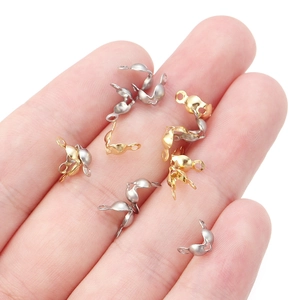 Macro view of tiny gold and silver bead tips on fingertip for size reference