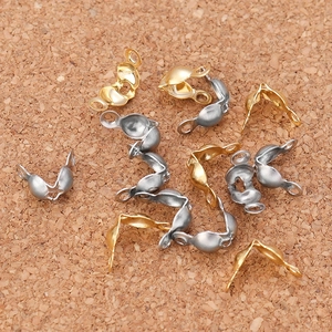 Macro shot of gold and silver bead tips for jewelry making on a cork surface
