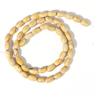 Macro shot of oval wooden beads with green and black spiral stripes on a white cord