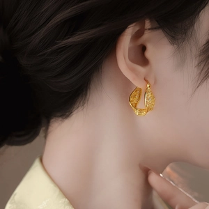 Gros plan détaillé de boucles d'oreilles créoles torsadées en filigrane d'or.