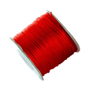 Detailed view of bright red Chinese knot cord roll on white spool for jewelry making