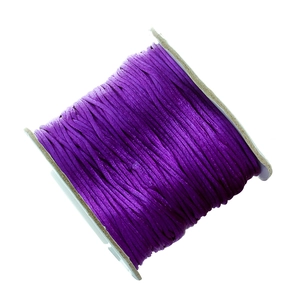 Close-up of shiny purple satin cord roll on paper spool for DIY jewelry making