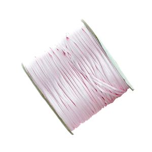 Detail of pink satin cord neatly wound on white reel for DIY jewelry making and crafts