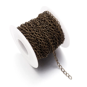Detail of vintage bronze metal chain roll on a white spool for DIY jewelry making