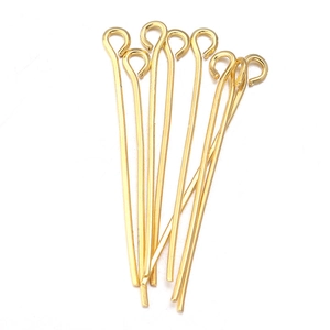 Close-up of golden eye pins for DIY jewelry making laid on a white background