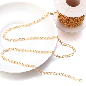 Golden long oval link chain for DIY jewelry making displayed on a white plate and spool