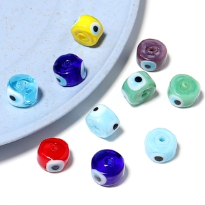 Perles en verre mauvais œil colorées pour bijoux DIY sur une assiette en céramique