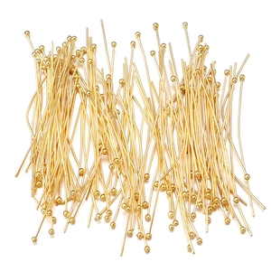 Macro view of golden ball head pins for jewelry making showing metallic shine and texture