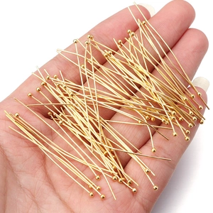 Golden copper ball head pins for DIY jewelry making held in hand for size comparison