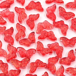 Close-up of red transparent butterfly beads with gold glitter for DIY jewelry making