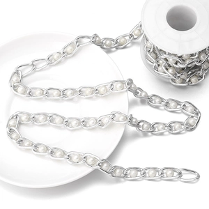 Detail of silver metal chain with white pearls on a spool for DIY bag strap decoration
