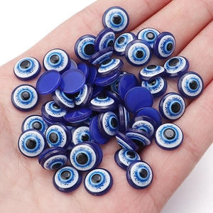 Detailed macro view of blue resin evil eye flatback beads held in a hand for size scale