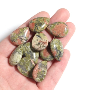Macro detail of a teardrop-shaped polished Unakite gemstone held in hand for DIY jewelry