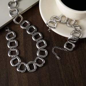 Dettaglio della collana e del bracciale a maglie quadrate in argento lucido su legno