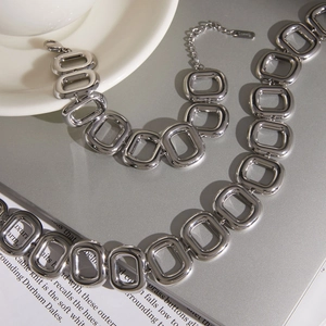 Dettaglio ravvicinato di collana e bracciale a maglie quadrate in acciaio al titanio argento.