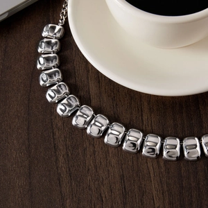 Dettaglio di una collana a maglie larghe color argento in acciaio inossidabile lucido