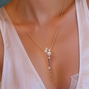 Detail view of a dainty silver necklace with zircon tassels and elegant pearls on model