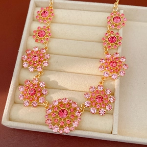 Detalle de un collar vintage dorado con cristales rosas en un joyero.