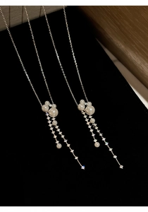 Detail view showing long zircon tassel and pearl pendant on a delicate silver chain
