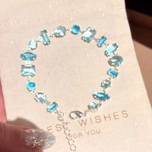 Detailed view of silver-toned bracelet with multi-shape light blue zircons on gift card