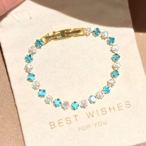 Dainty gold-plated bracelet featuring blue and white square zircons on textured display card