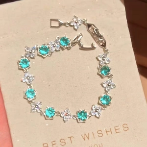 Close-up detail of a silver-toned flower bracelet with turquoise and white zircons.