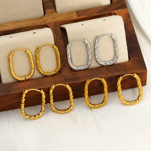 Detailed macro shot of textured gold and silver oval hoop earrings on wooden display