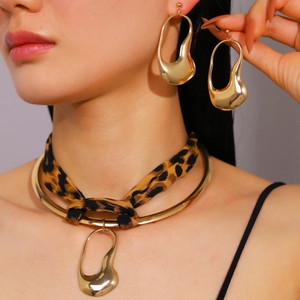 Close-up of irregular liquid gold earrings and leopard ribbon choker necklace set