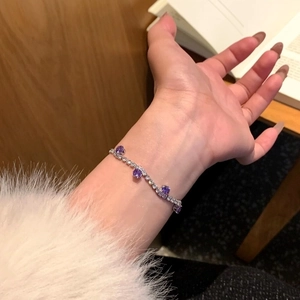 Elegantes silbernes Armband mit violetten und klaren Zirkonia am Handgelenk einer Frau.