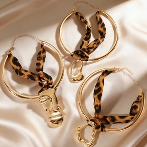 Detailed view of gold hoop chokers with leopard print ribbons and abstract pendants