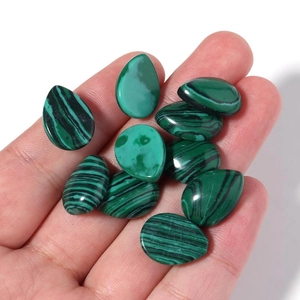 Polished teardrop and oval malachite gemstones with green banded texture on palm
