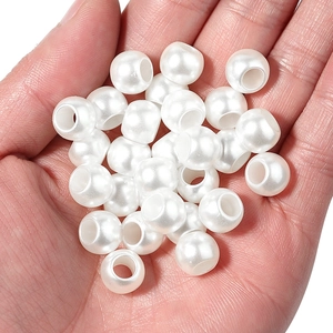 Dettaglio di perle bianche ABS a foro largo tenute in mano per la creazione di gioielli DIY
