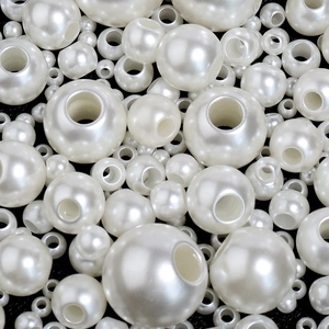 Vista macro di perle finte beige di varie dimensioni con grandi fori per gioielli fai da te