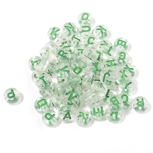 Macro detail of transparent acrylic alphabet beads with green letters for DIY bracelets