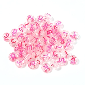 Macro view of clear acrylic alphabet beads with pink marble texture for DIY jewelry