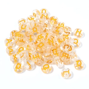 Close-up of transparent acrylic round alphabet beads with golden A-Z letters for DIY crafts