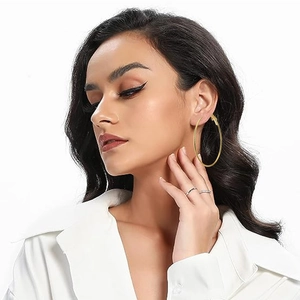 Close-up of a model wearing large gold plated hoop earrings with a smooth polished finish