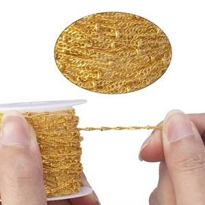 Detail of 1.5mm gold plated copper flat beaded curb chain on white spool for DIY jewelry