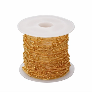 Macro shot of 1.5mm golden satellite bead chain wound on a white plastic spool
