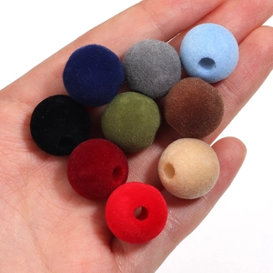Vista macro de cuentas de acrílico flocado multicolor de 16mm con agujeros en la mano