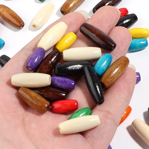 Close-up of colorful tube-shaped maple wood beads for DIY jewelry making held in hand
